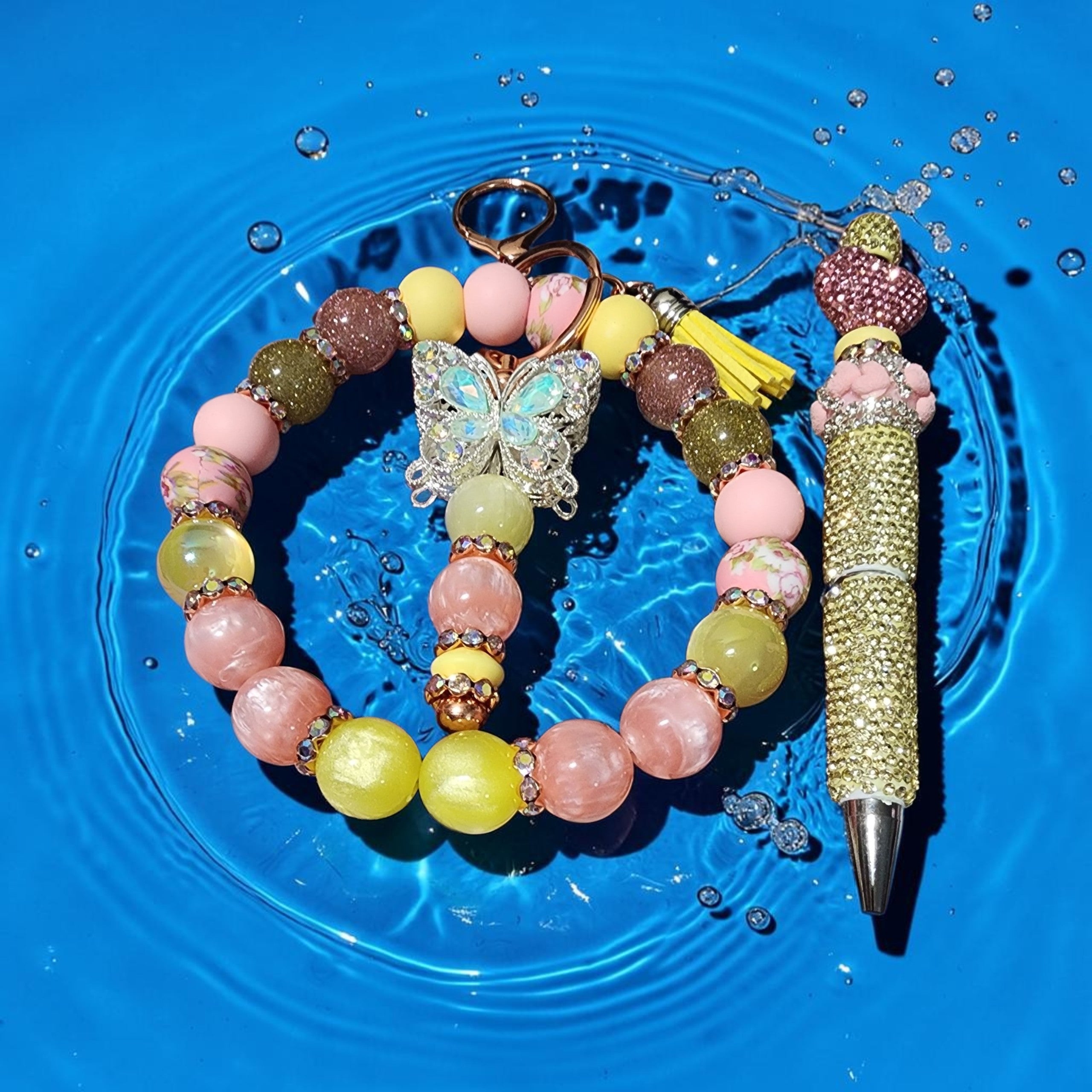 Blessed Bead worx pastel beaded bracelet with butterfly charm and matching rhinestone pen on a blue water background